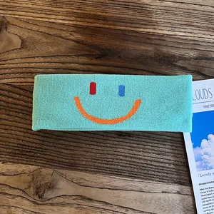 Détail d'un bandeau de sport en tricot vert menthe avec broderie smiley colorée