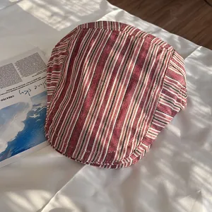 Detail of classic striped flat cap with red and brown vertical stripes on soft fabric