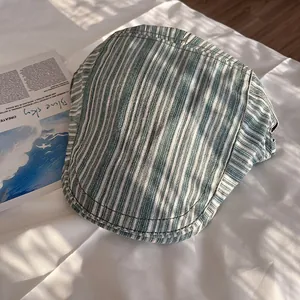 Detail of green and white striped ivy cap on fabric with artistic window shadows