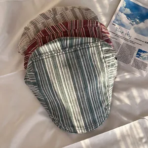Three vintage striped flat caps in olive green, burgundy, and beige on white fabric