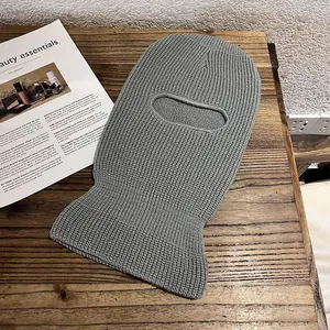 Detailed knit texture of a grey single-hole balaclava mask on a wooden surface