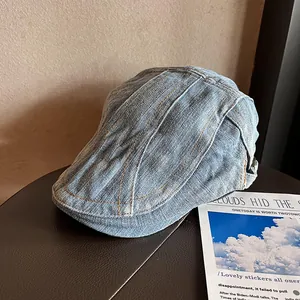 Close-up of vintage blue denim newsboy cap with orange contrast stitching and twill texture