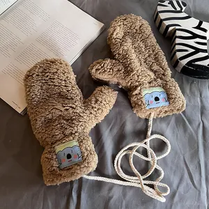 Detail of plush lamb wool mittens in brown featuring a cute koala patch and neck string
