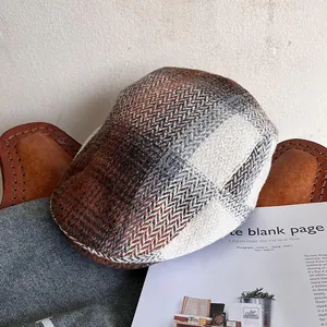 Detail of vintage herringbone newsboy cap on brown leather and denim with magazines