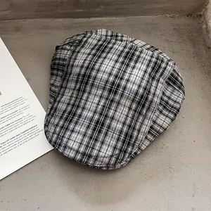 Detailansicht einer klassisch schwarz-weiß karierten Schiebermütze auf strukturiertem Grund