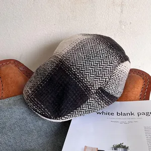 Detail view of retro herringbone wool newsboy cap on vintage leather and denim background