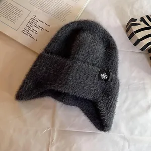 Detail of dark grey plush knit hat with snowflake label and soft fuzzy texture