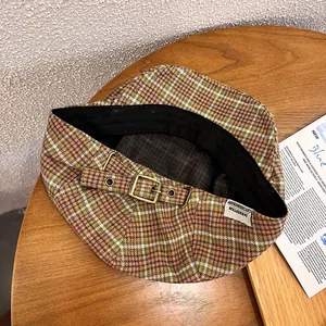 Detailed close-up of retro plaid beret featuring bronze buckle and woven fabric texture