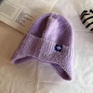 Detail of purple knit ear-flap hat with soft fuzzy texture and snowflake patch