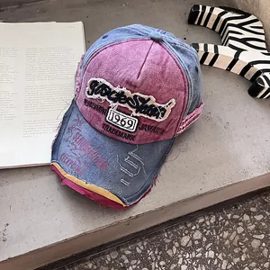 Détail d'une casquette denim vintage avec broderie Rockstar et bordure à franges usée