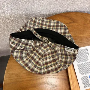 Detail of retro plaid beret with adjustable bronze metal buckle on wooden table