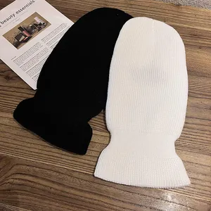 Knitted balaclava face mask in black and white styles on a rustic wooden background