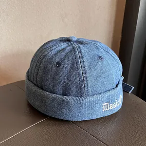 Dettaglio del berretto docker in denim lavato blu scuro con ricamo bianco 'Magic'