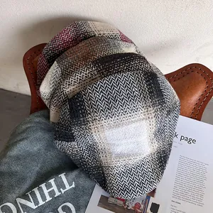 British vintage herringbone and plaid newsboy caps stacked on a leather chair