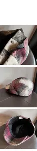Detailed close-up of plaid newsboy cap with wool texture and metal buckle detail