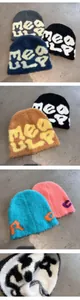 Detailed close-up showing plush knit beanies with jacquard lettering in multiple colors