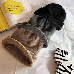 Casquettes tricotées d'hiver en noir, gris et kaki sur un fond de tissu blanc doux