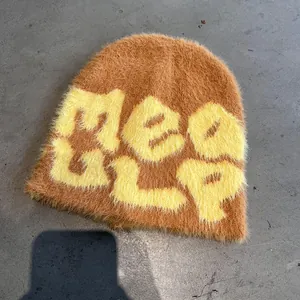 Detail shot of fuzzy knit beanie with yellow MEAGLP lettering on fluffy ginger base
