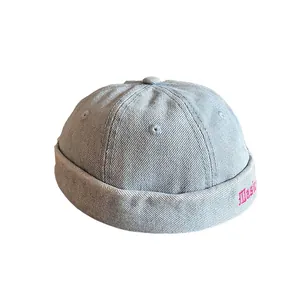 Berretto docker in denim azzurro con ricamo rosa e design vintage con bordo arrotolato