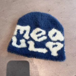 Detail of blue plush beanie with white MEQ ULP lettering showing fuzzy mohair texture