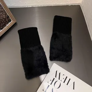 Detailed view of black knitted fingerless gloves with thick faux fur trim on a desk