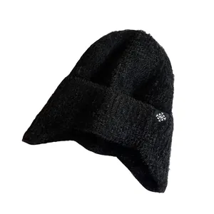 Thick black knitted earflap hat for women with fuzzy texture and snowflake patch label