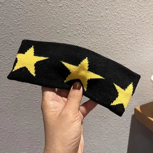 Detail view of black knitted star headband featuring three yellow jacquard star patterns