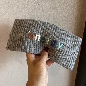 Gros plan d'un bandeau en maille grise avec lettres energy 3D colorées tenu à la main