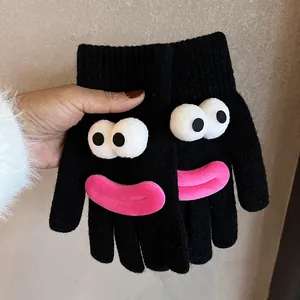 Close-up of black knitted gloves featuring a quirky cartoon face with large eyes and pink lips