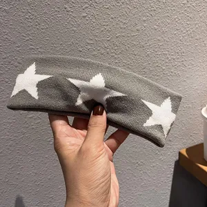 Close-up of gray knitted headband featuring three white star patterns in hand