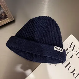 Detailed texture of dark blue ribbed knit beanie featuring an NTRX woven label