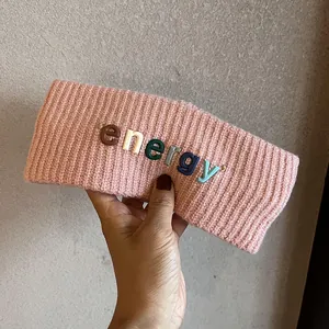 Détail du tricot d'un bandeau rose large avec des lettres colorées energy en relief