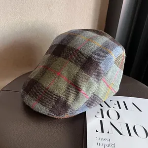 Detail view of the vintage plaid wool fabric texture on a retro green newsboy flat cap
