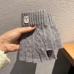 Close-up of grey knitted fingerless gloves with a vintage deer logo leather patch