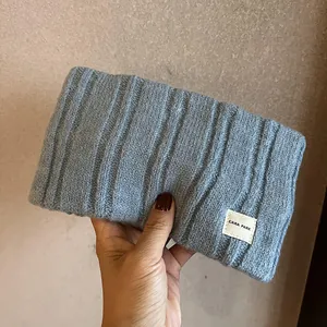 Detail of gray knitted headband showing soft ribbed wool texture and brand logo label