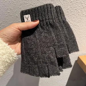 Close-up of dark grey knitted fingerless gloves with a deer logo patch on the ribbed cuff