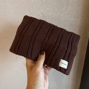 Detail of dark coffee ribbed knit headband showing soft wool texture and logo label