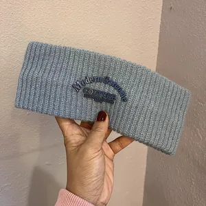 Macro detail of grey knitted headband with navy blue embroidered fashion label