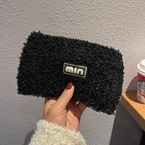 Close-up of black teddy fleece headband featuring a central min woven brand label