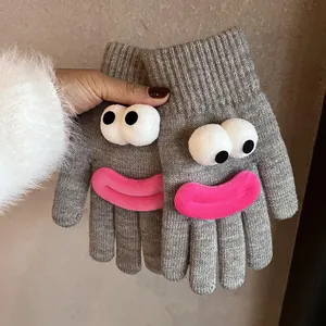 Detail of grey knitted gloves featuring funny cartoon 3D eyes and pink plush lips