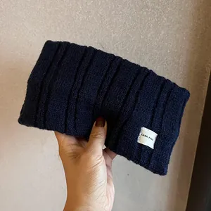 Knitted navy blue ribbed headband for women with a white letter label and soft texture
