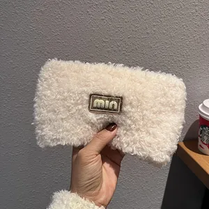 Detail view of a soft beige teddy fleece pouch with a minimalist brown logo patch