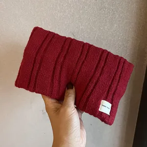 Detail showing deep red ribbed knit fabric texture and minimalist brand label on the headband