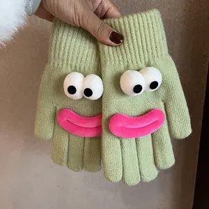 Detail of green knitted gloves featuring funny cartoon eyes and pink plush lips