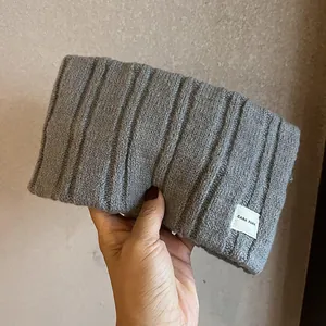 Close-up of gray knitted headband featuring vertical ribbed texture and logo label
