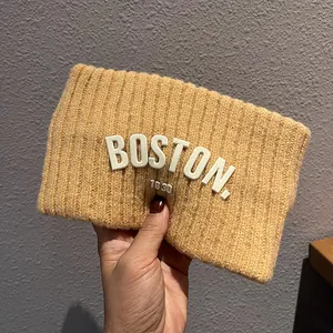 Détail de la texture tricotée du bandeau d'hiver jaune gingembre avec lettrage Boston