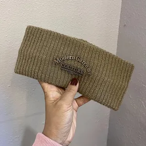 Detail of a brown ribbed knit headband with an oval vintage couture logo patch