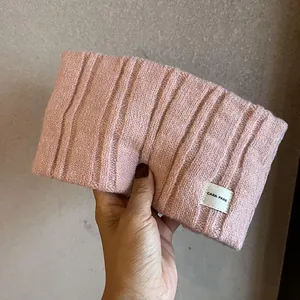 Detail of pink knitted headband featuring ribbed texture and white logo brand label