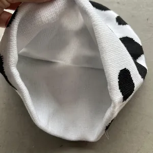 Knit beanie featuring a cow pattern with a close-up of the warm white inner lining