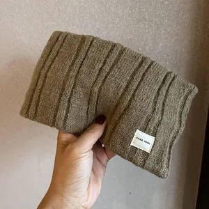 Detailed view of coffee brown knit headband with rib texture and white logo label